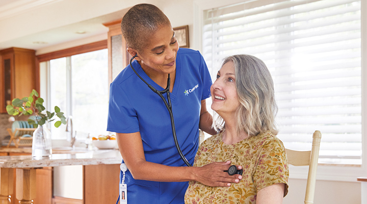 A CenterWell Home Health clinician listening to a patient's heart in her kitchen