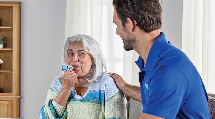 A CenterWell Home Health clinician testing a patient's lung function in her home