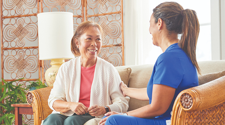A CenterWell Home Health clinician and patient sitting and talking on the patient's couch
