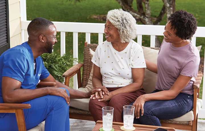 Female clinician speaks with elderly couple in their living room